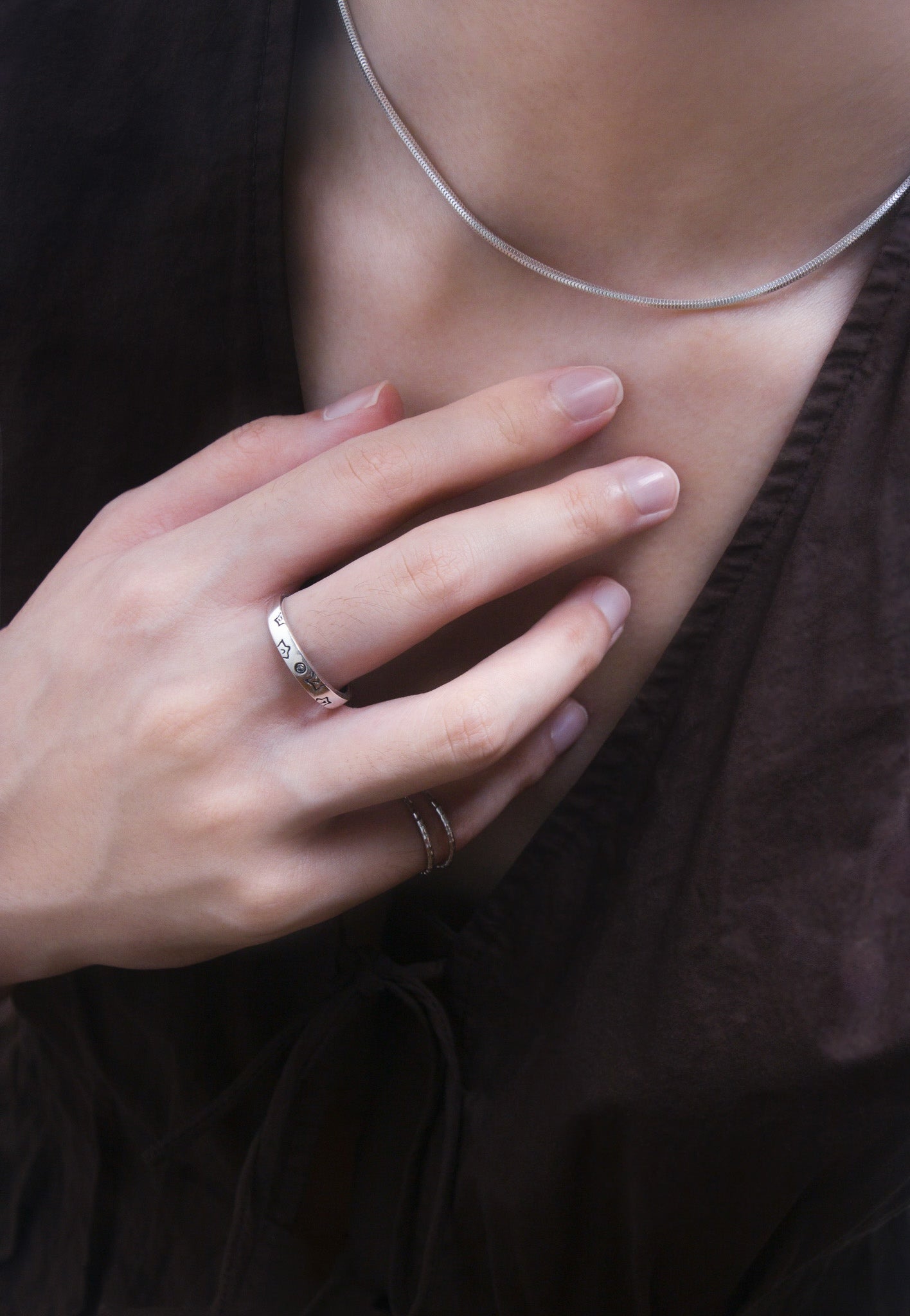 Close-up front view of a person's hand with silver rings on a dark background
