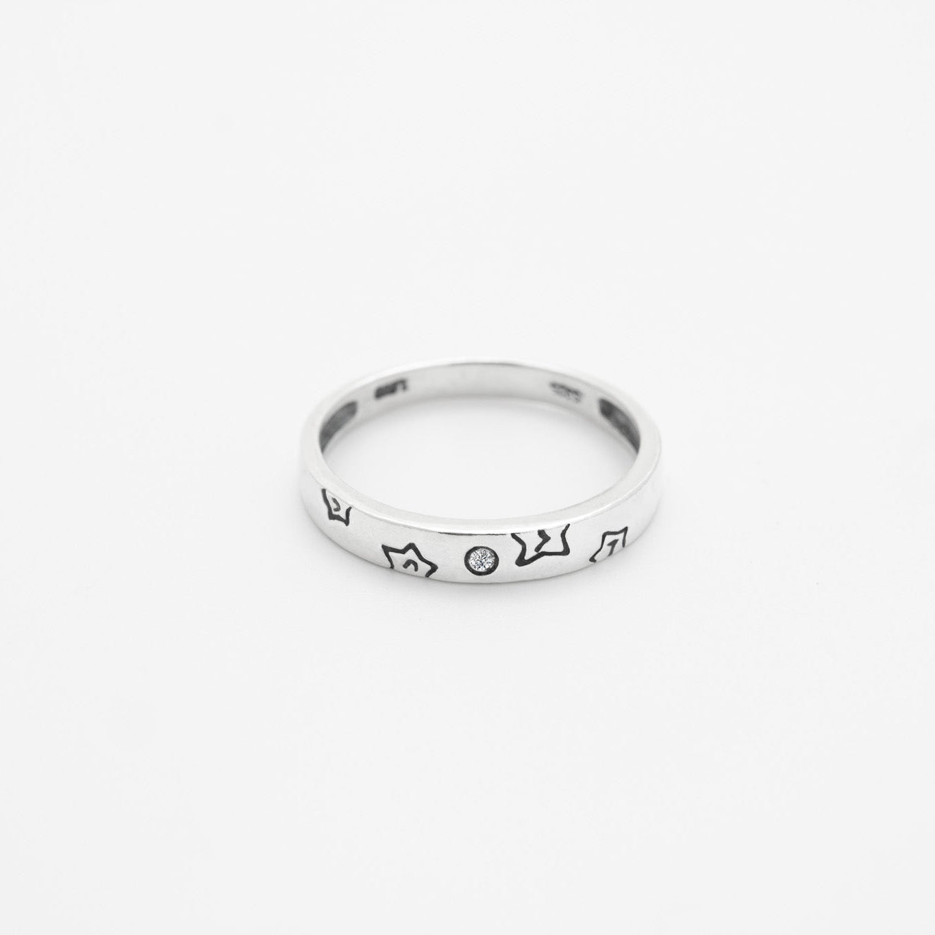 Silver ring with engraved design on a white background, close up top down view