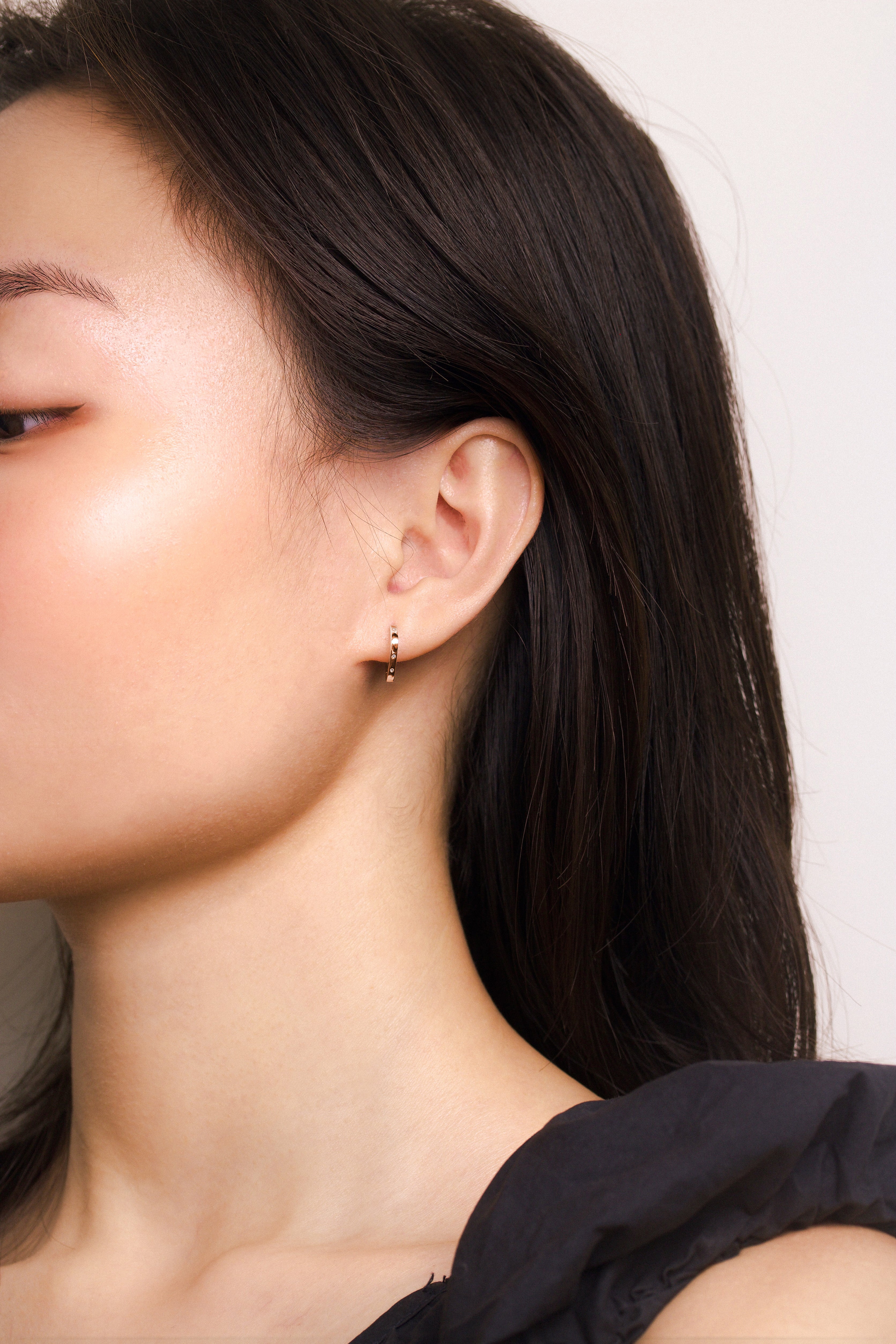 Fine jewellery, silver jewellery plated with rose gold, hypoallergenic, tarnish-free, full front view of a rose gold hoop earrings with crystals worn on a person's ear