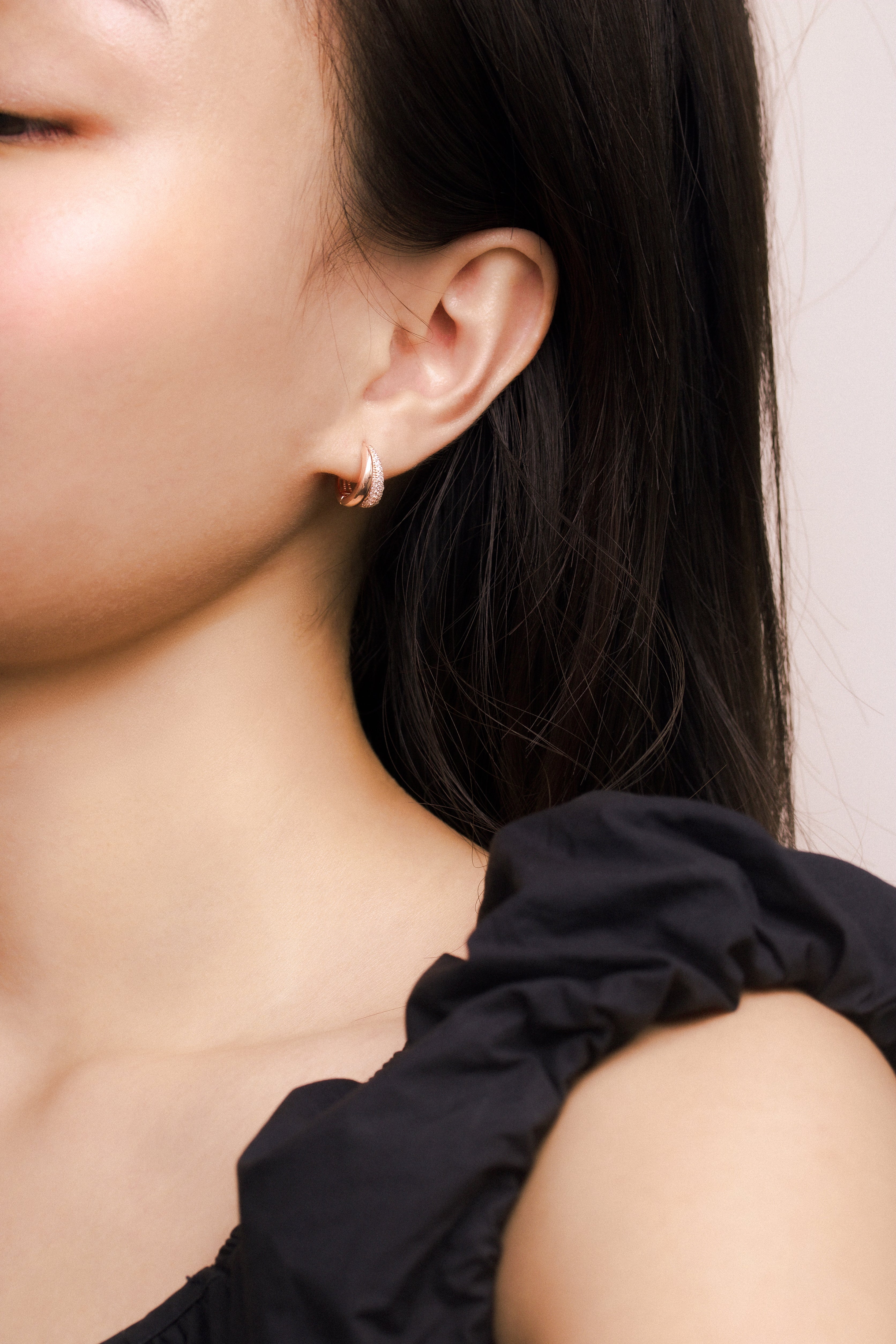 Fine jewellery, silver jewellery plated with rose gold, hypoallergenic, tarnish-free, close-up front view of a Pair of rose gold crystal earrings, full left view of a person wearing rose gold hoop crystal earrings with a neutral background