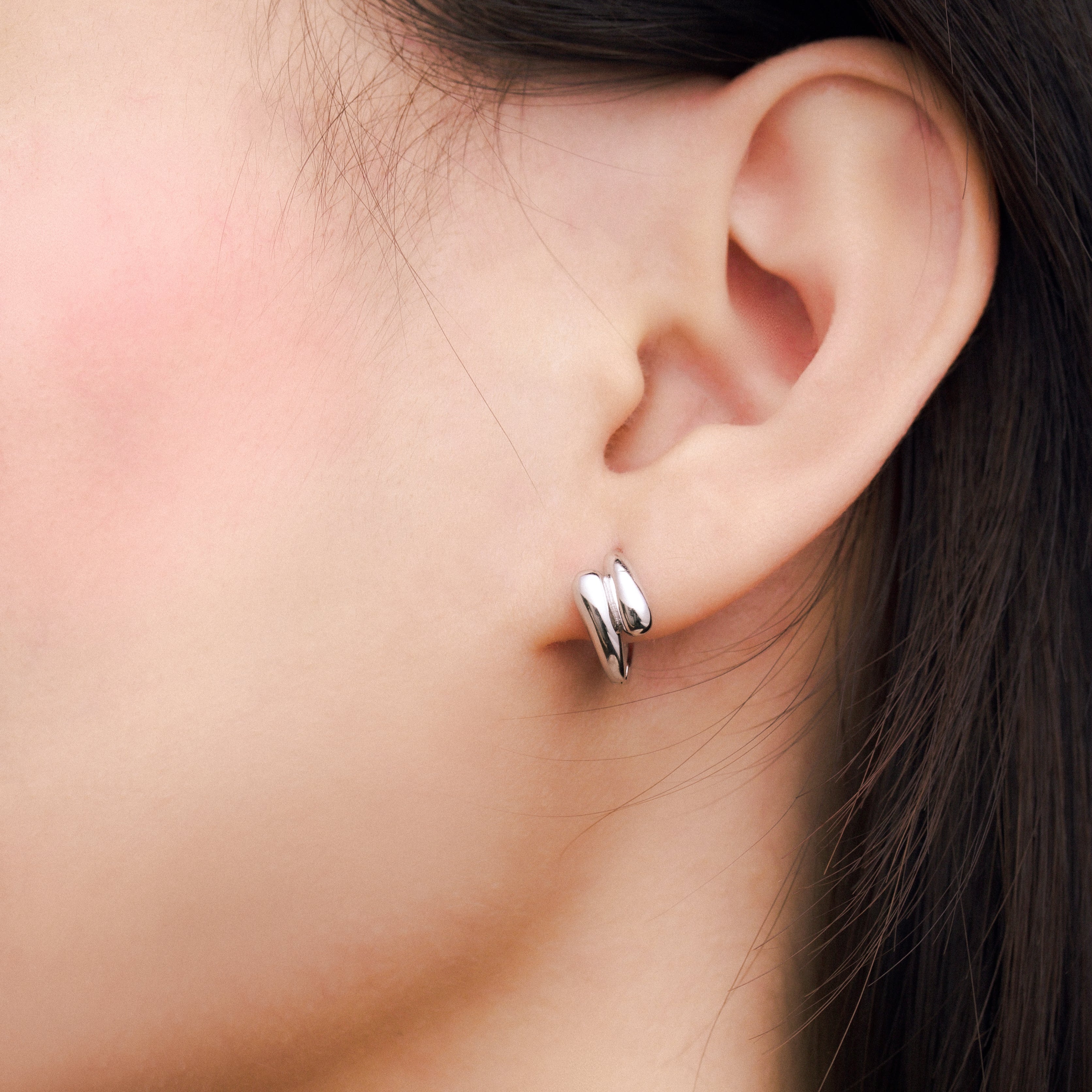 Fine jewellery, silver jewellery, hypoallergenic, tarnish-free,
Close-up side view of a person wearing a silver hoop earring.