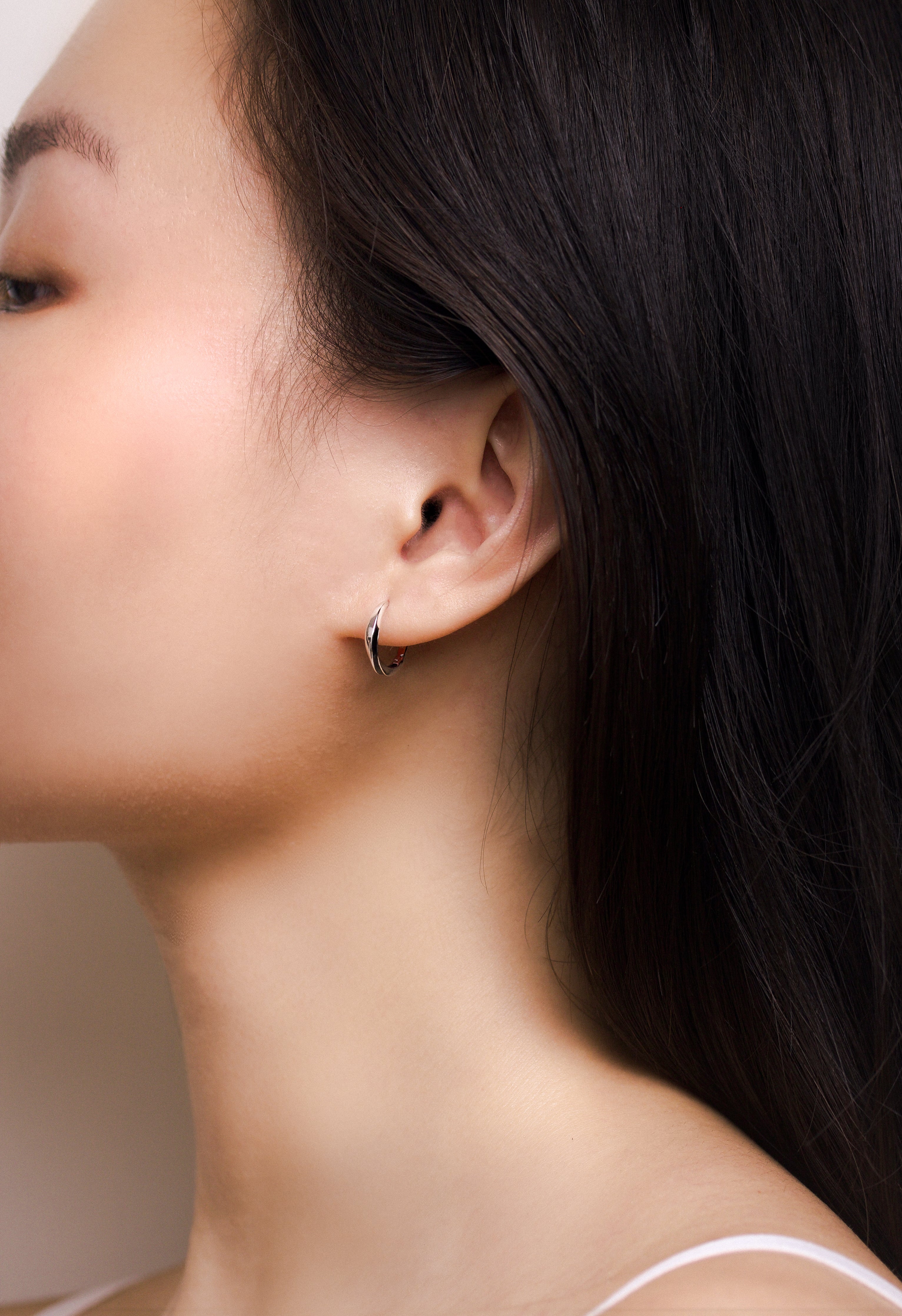 Fine jewellery, silver jewellery, hypoallergenic, tarnish-free, full left view of a Pair of silver glazed black hoop earrings worn on a person's ear