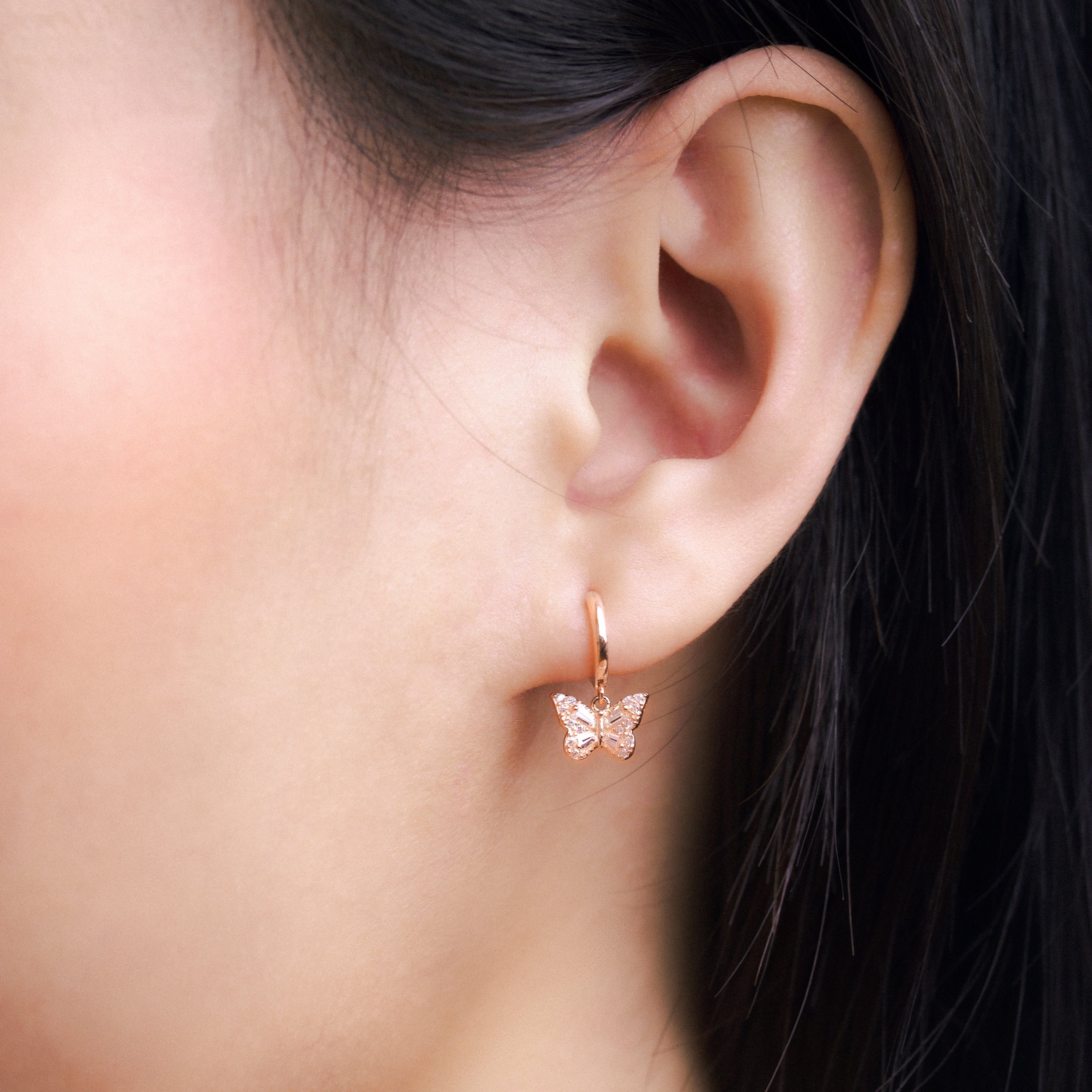 Fine jewellery, silver jewellery plated with rose gold, hypoallergenic, tarnish-free, Close-up front view of an ear wearing a butterfly-shaped earring with a blurred background
