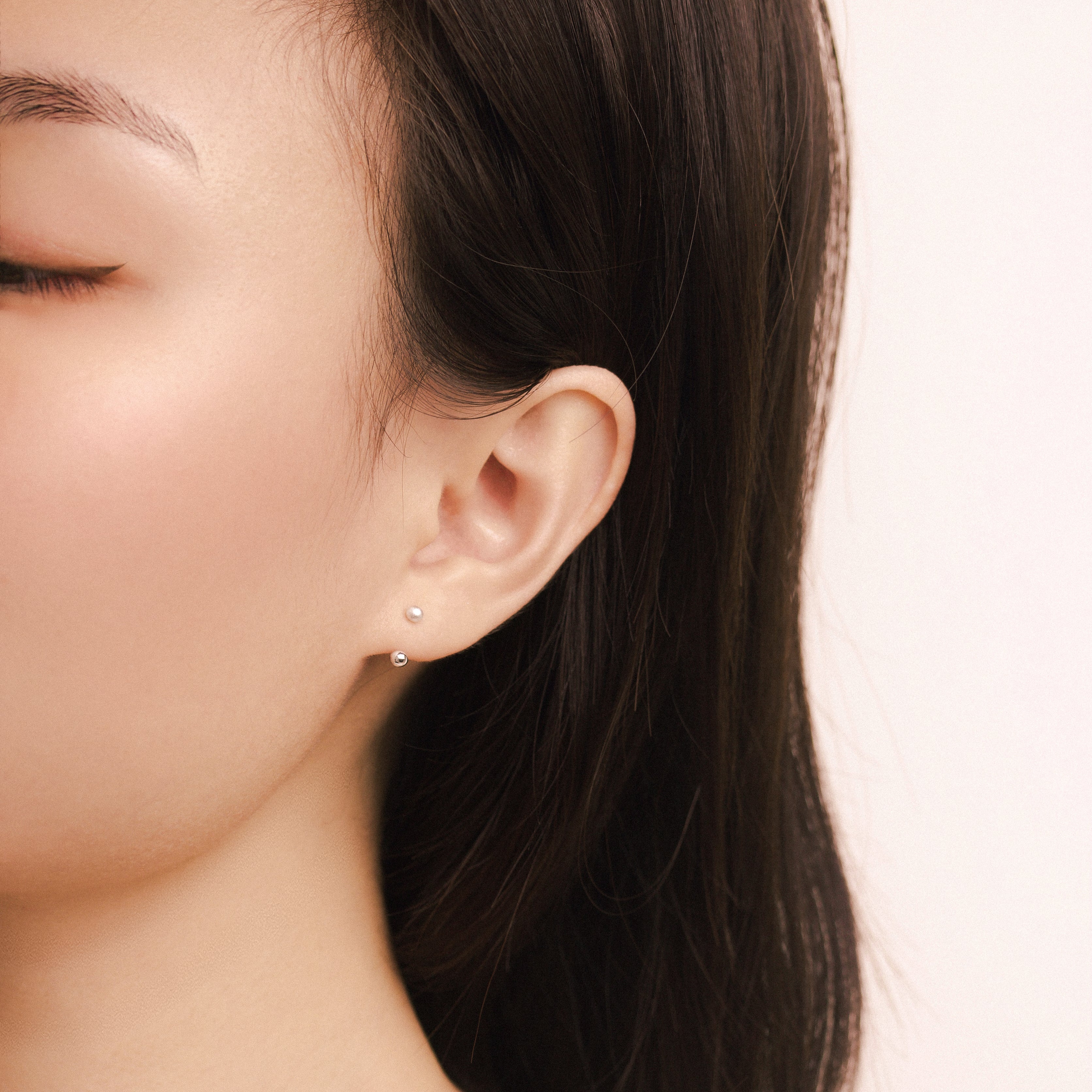 Fine jewellery, silver jewellery, hypoallergenic, tarnish-free, full side view of a person wearing a small silver ear studs with a plain background