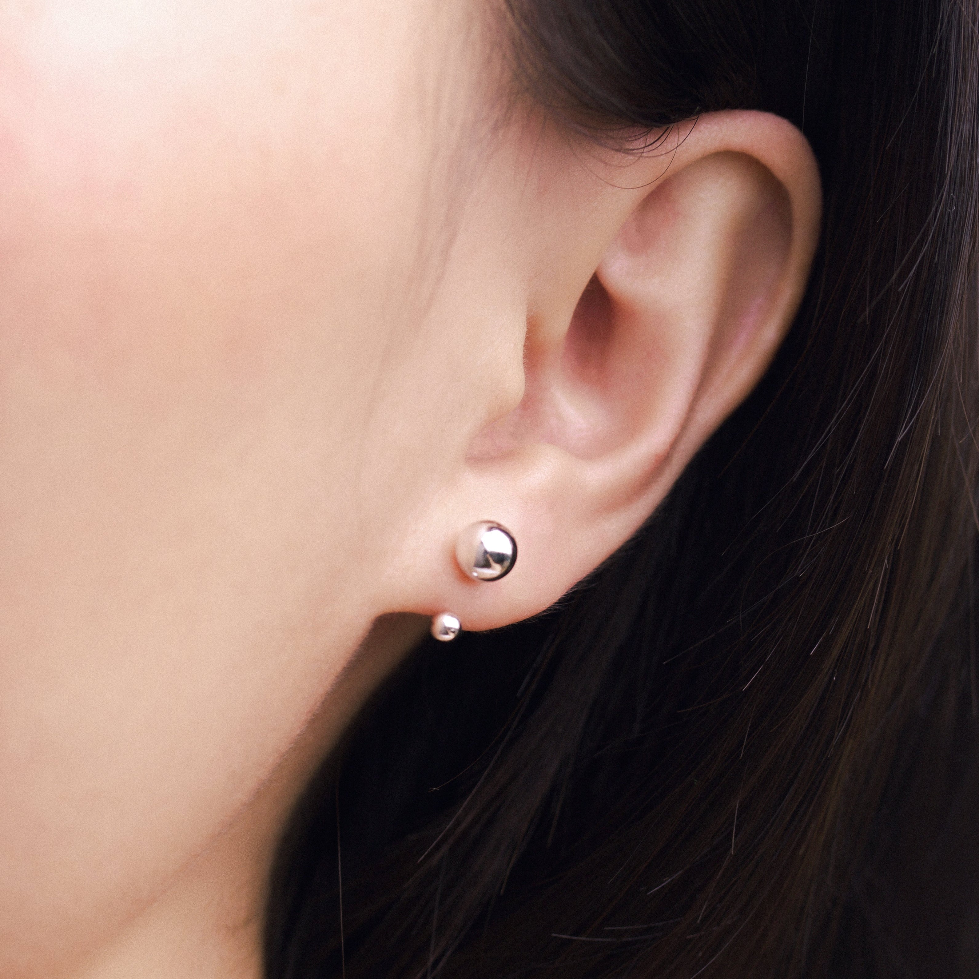 Fine jewellery, silver jewellery, hypoallergenic, tarnish-free, Close-up side view  of an ear wearing a silver earring with a silver spherical ends
