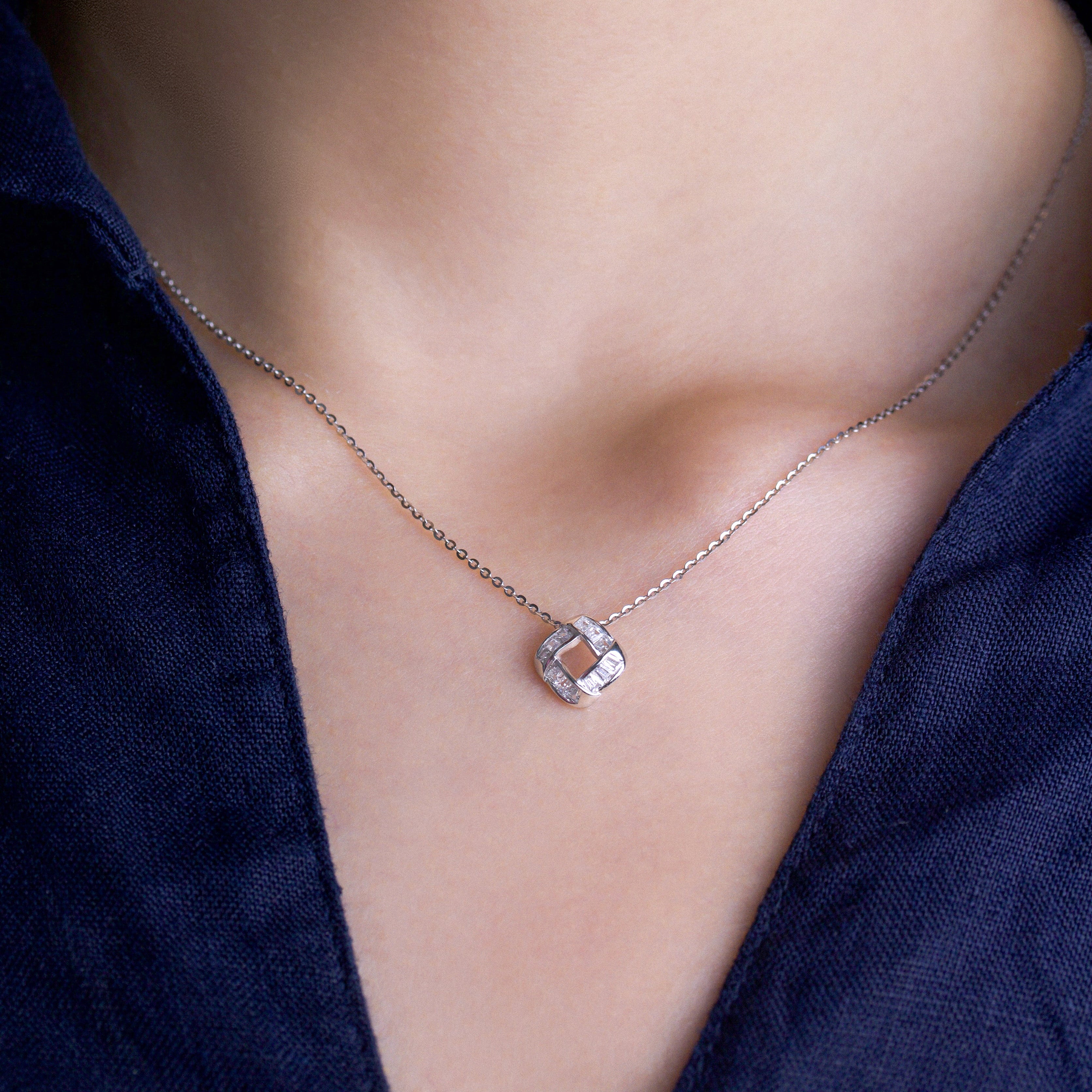 Fine jewellery, silver jewellery, hypoallergenic, tarnish-free, front close-up of a Silver necklace with a diamond pendant on a person wearing a dark blue top.