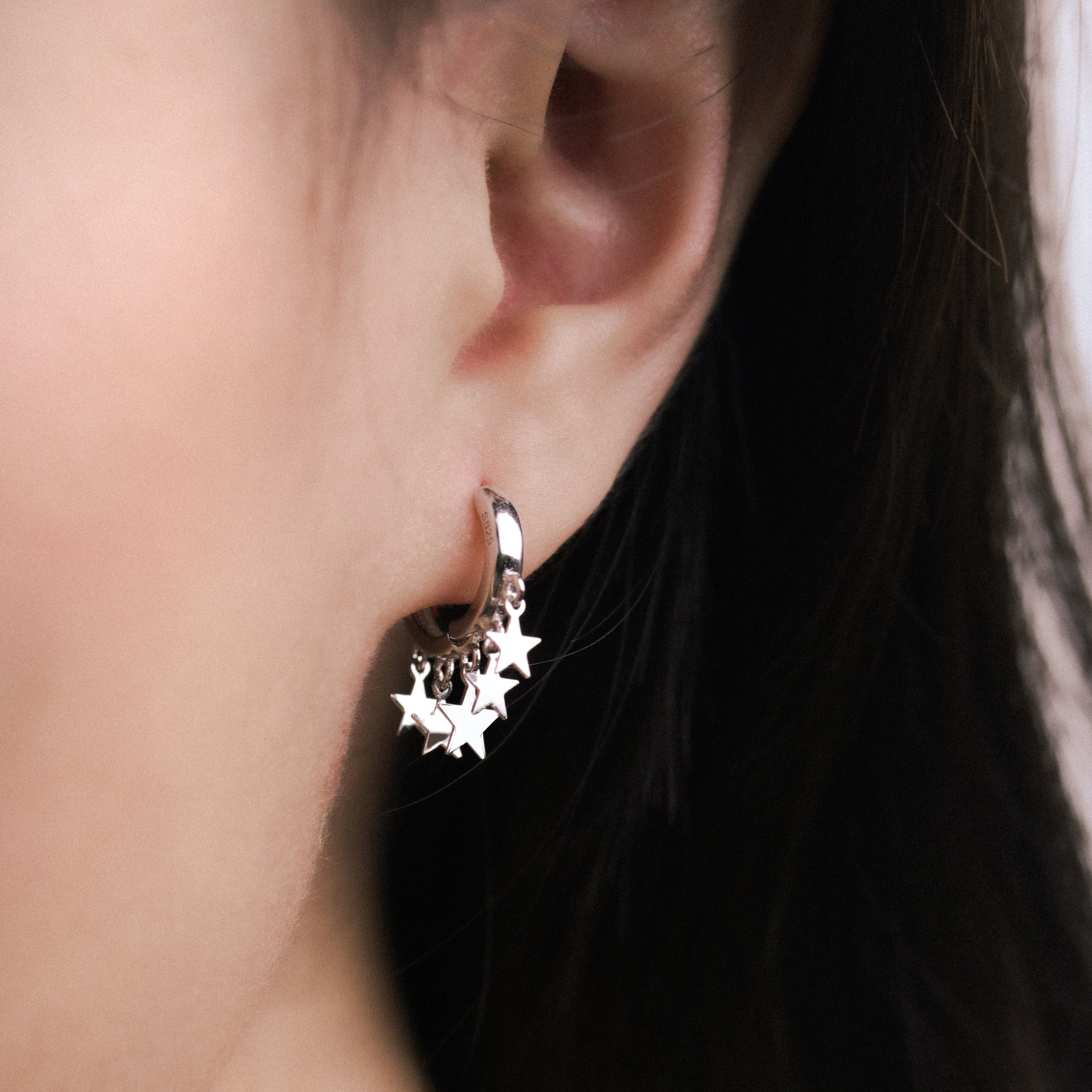 Fine jewellery, silver jewellery, hypoallergenic, tarnish-free, side view Close-up of an ear wearing a silver star-shaped earring.