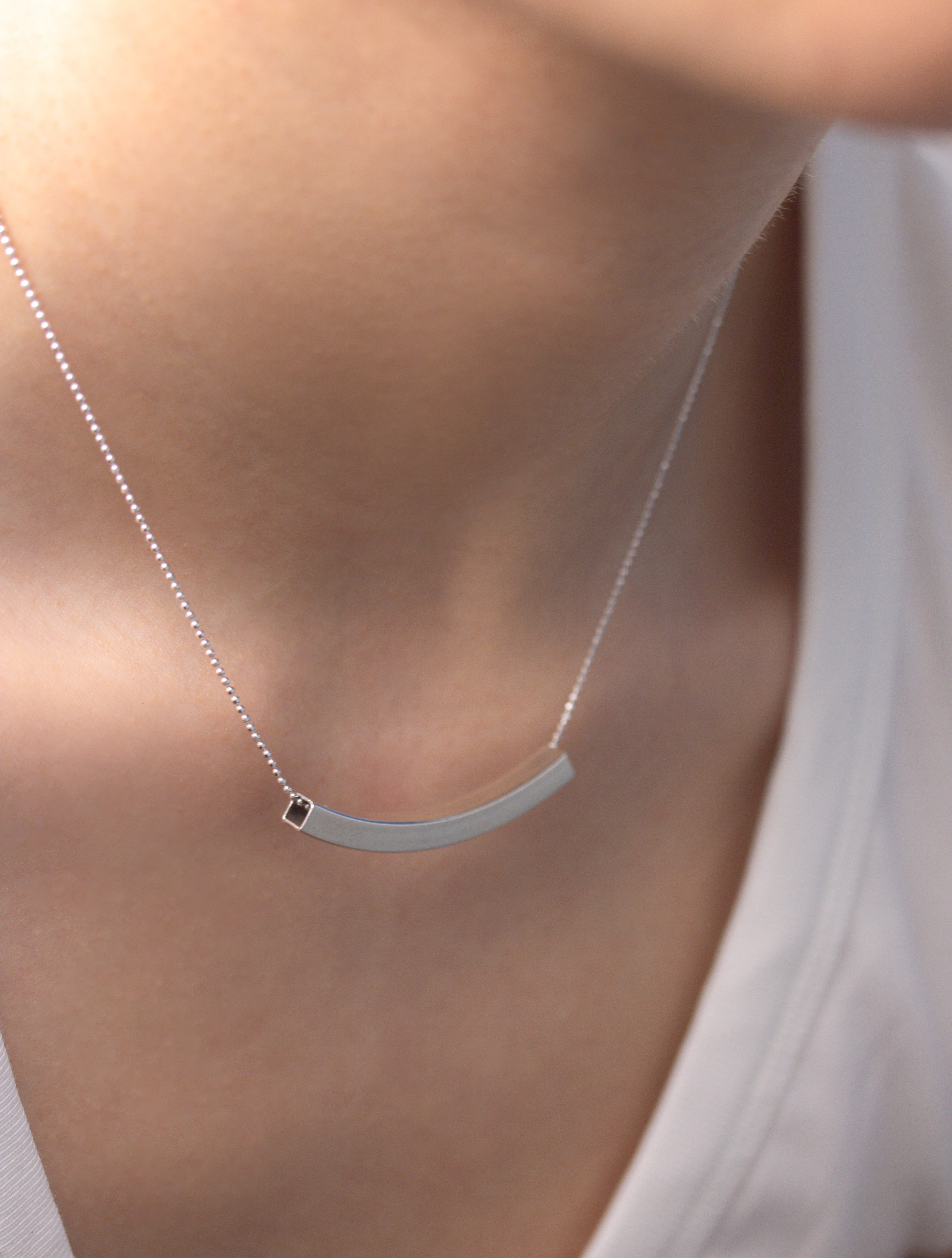 Fine silver jewellery, silver necklace, Pendant necklace, Hypoallergenic, Tarnish-free, close up side view Silver pendant necklace with a curved pendant on a person leaning forward to showcase details