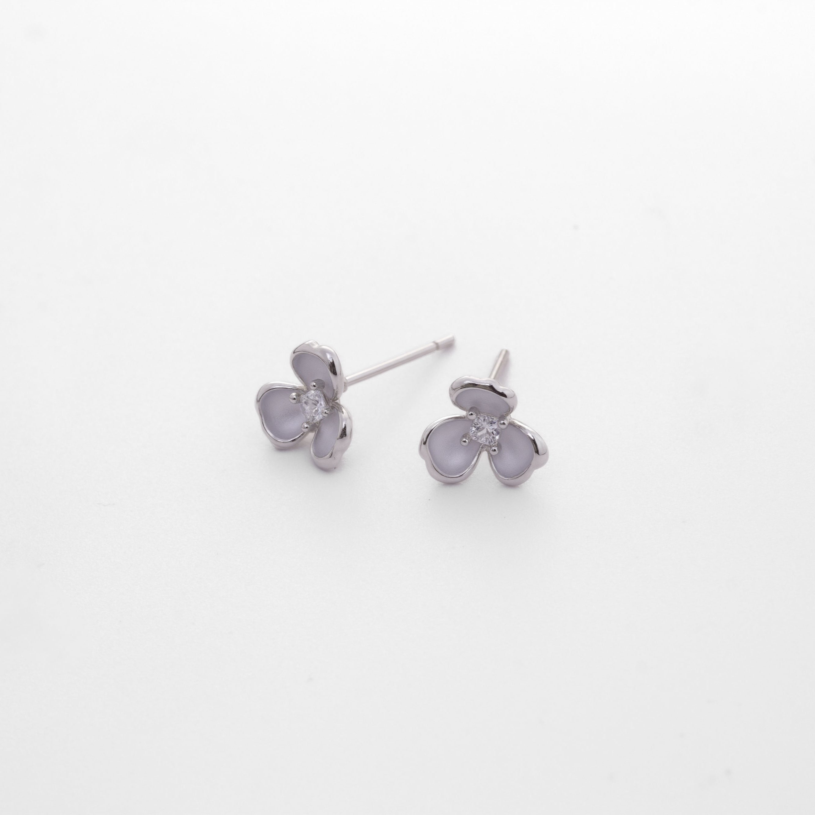 Fine jewellery, silver jewellery, hypoallergenic, tarnish-free, close-up overlooking view of a Pair of silver ear studs shaped like flower in a light grey background