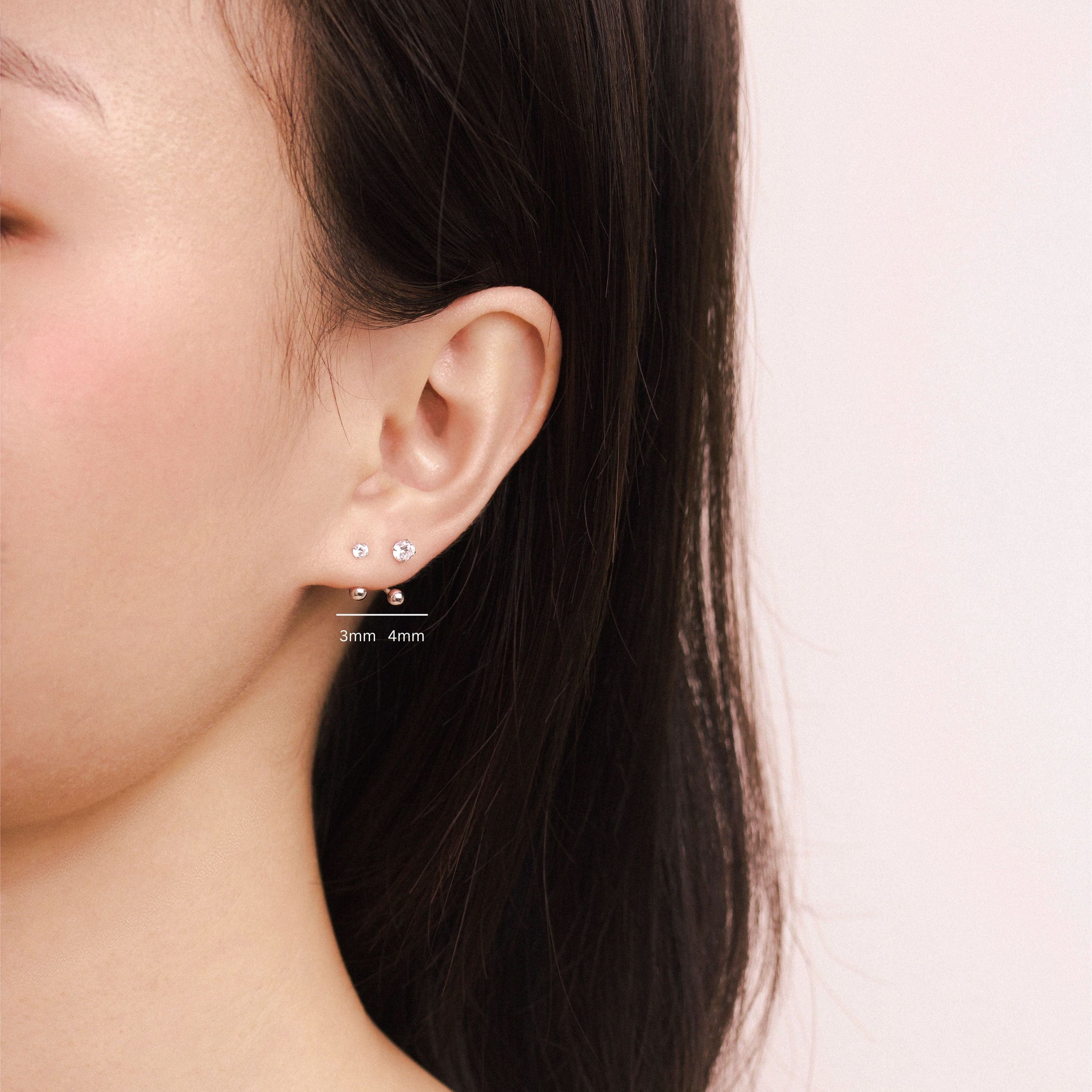 Fine jewellery, silver jewellery, hypoallergenic, tarnish-free, Front view Close-up of a person wearing a crystal earring with silver spherical ends, labelled with 3mm and 4mm of different crystal size