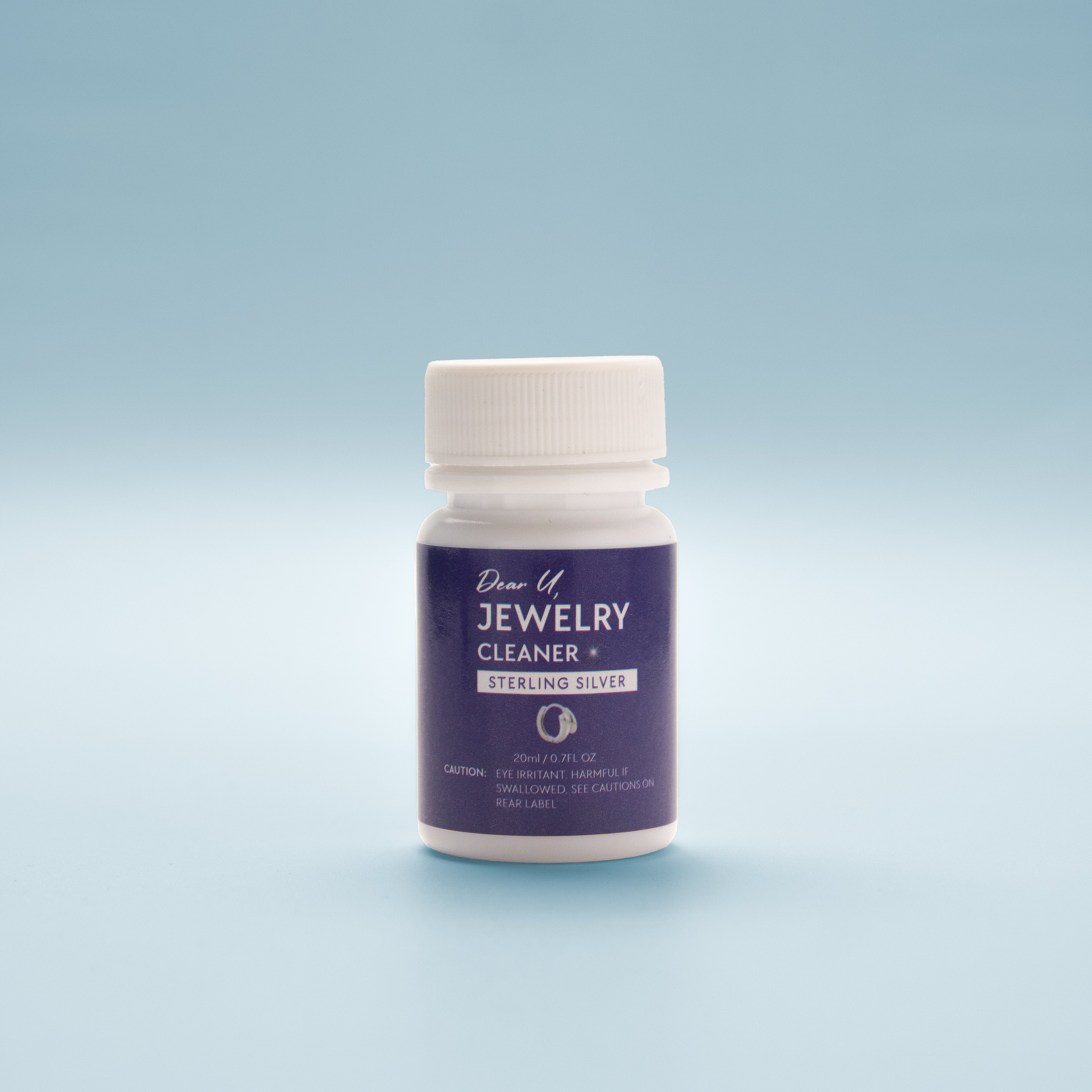 Close-up front view Jewellery cleaner bottle with blue label on a light blue background