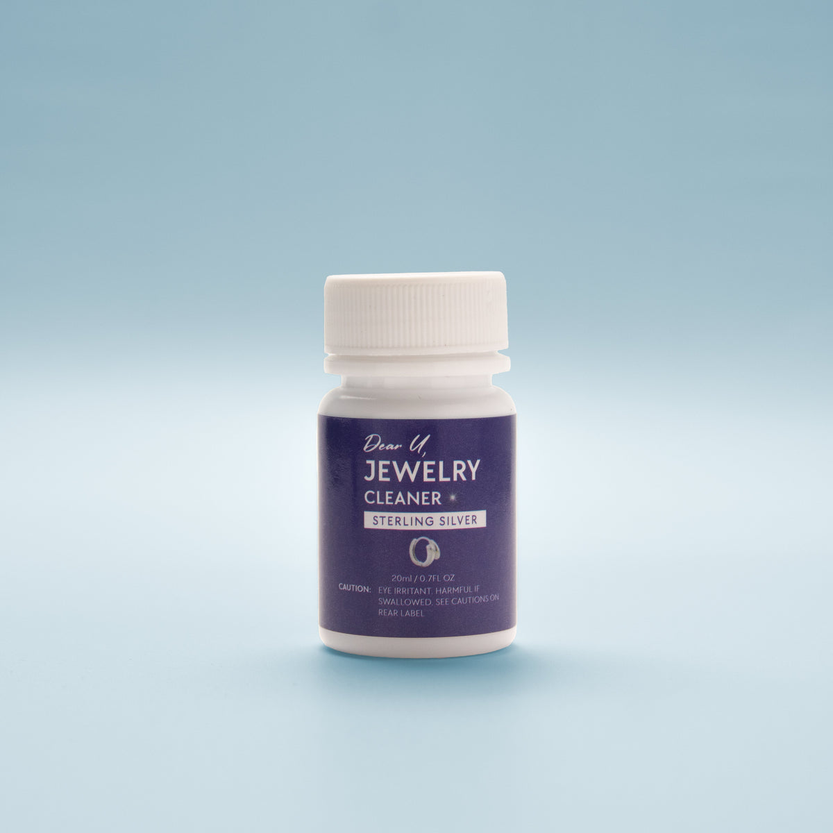 Close-up front view Jewellery cleaner bottle with blue label on a light blue background