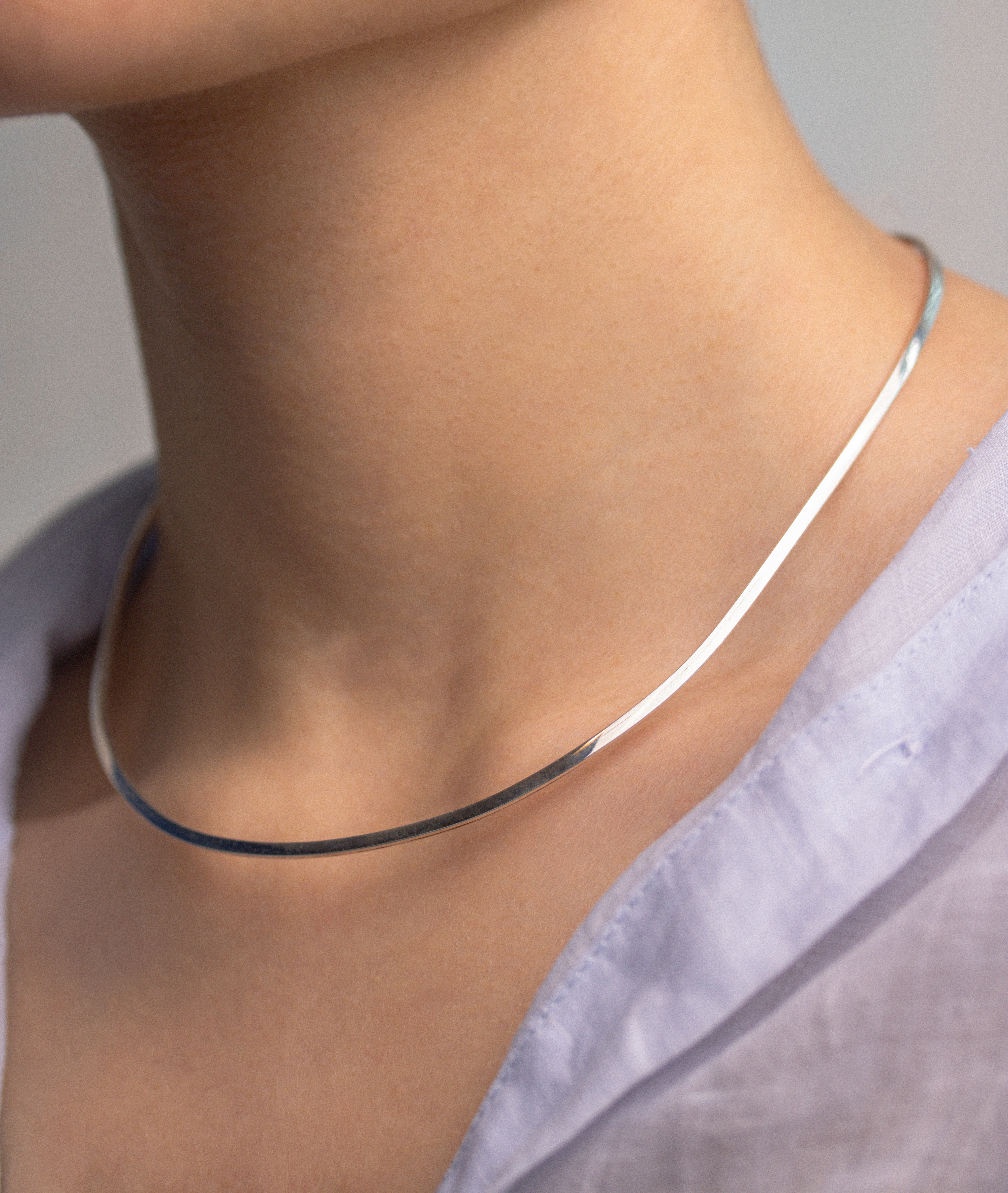 Fine Italian Jewellery, silver jewellery, hypoallergenic, tarnish free, Side view of a Silver choker on a person wearing a light blue shirt against a neutral background