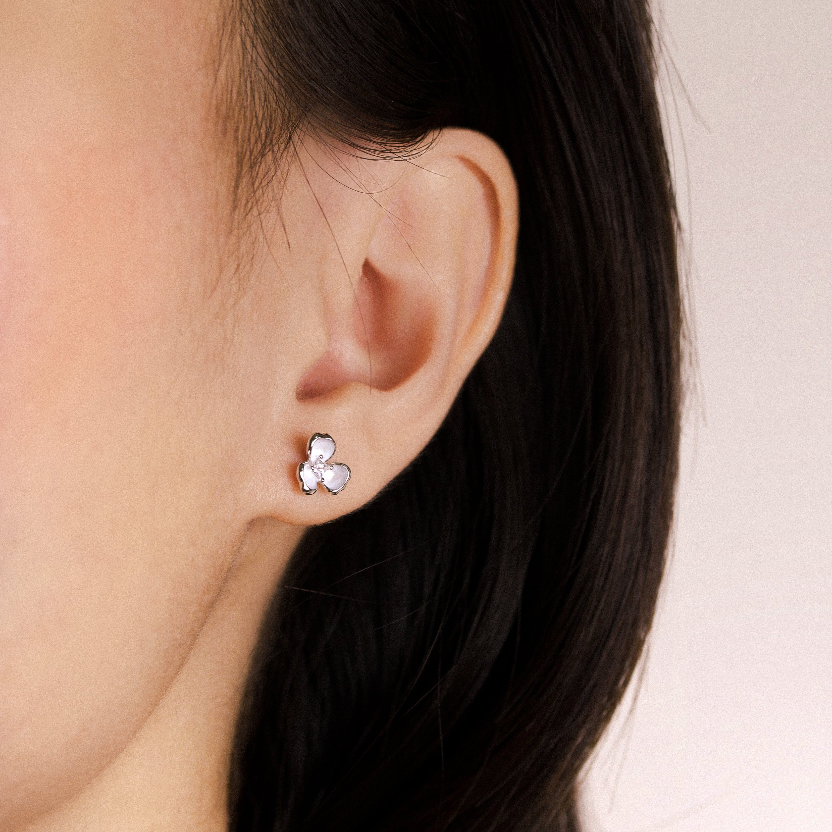 Fine jewellery, silver jewellery, hypoallergenic, tarnish-free, close-up right view of a silver ear studs shaped like flower worn on a person's ear