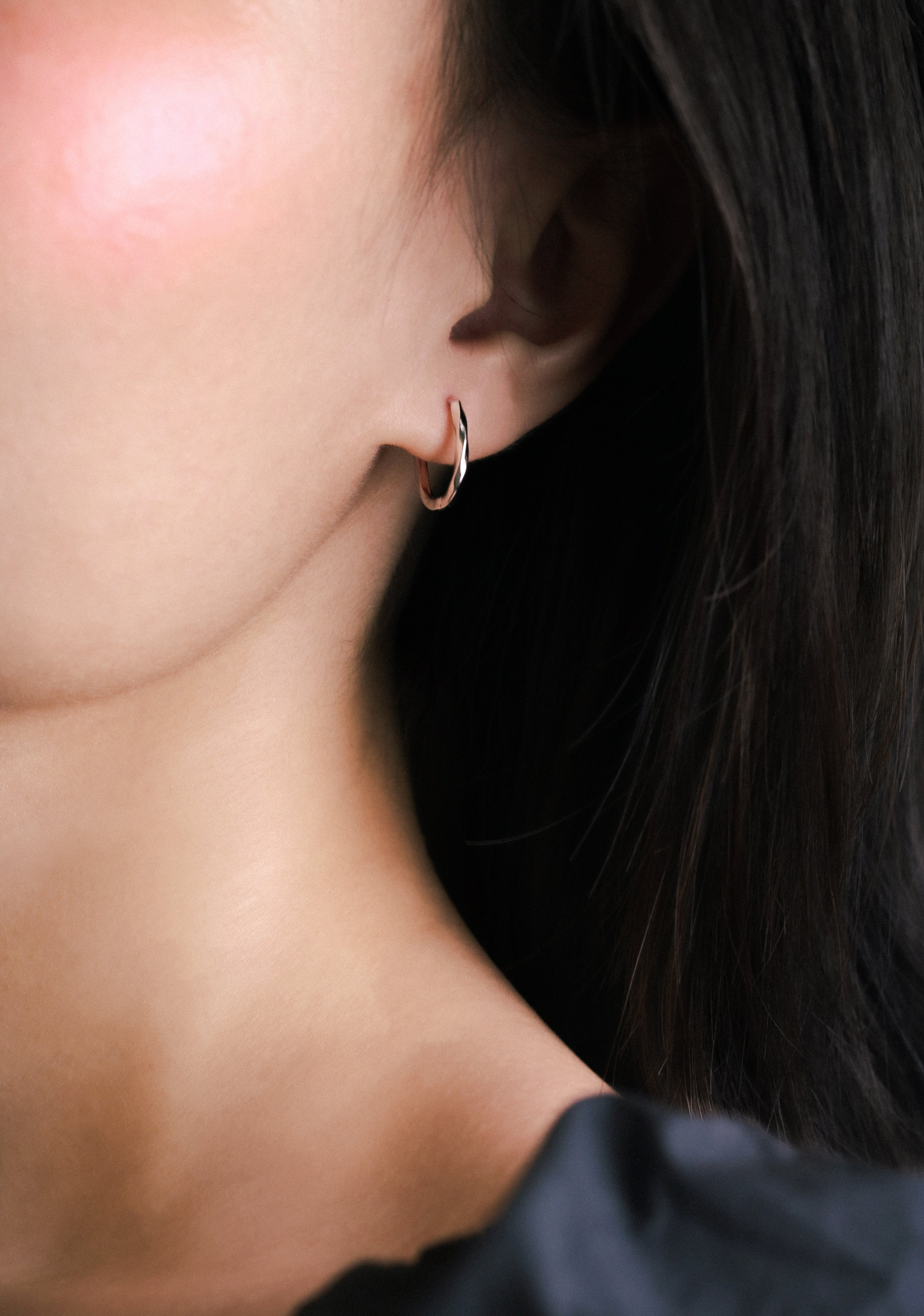 Fine jewellery, silver jewellery, hypoallergenic, tarnish-free, full side view of a person wearing a silver hoop earring with a blurred background