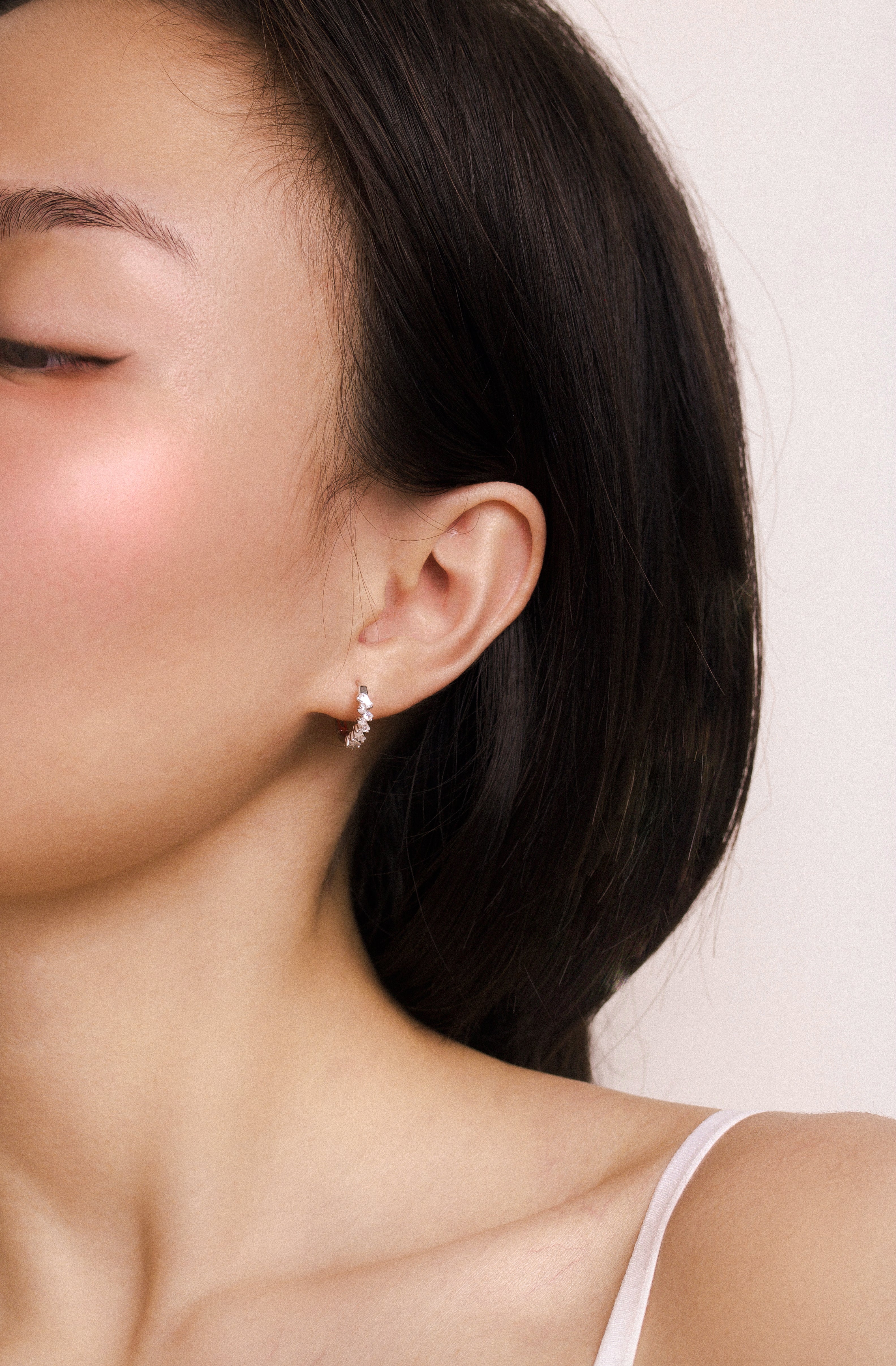 Fine jewellery, silver jewellery, hypoallergenic, tarnish-free, full side view of a person wearing a crystal hoop with a plain background