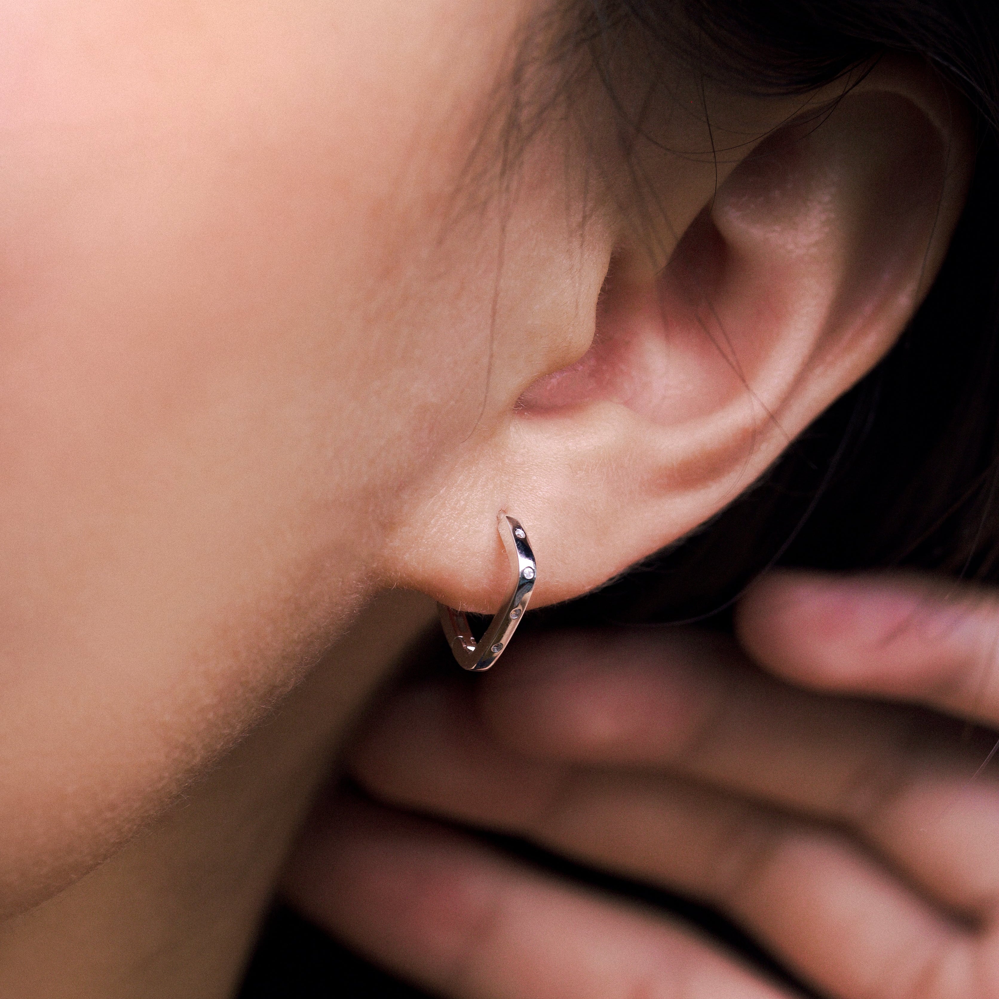 Fine jewellery, silver jewellery, hypoallergenic, tarnish-free, close-up side view of a silver hoop earrings with crystals worn on a person's ear
