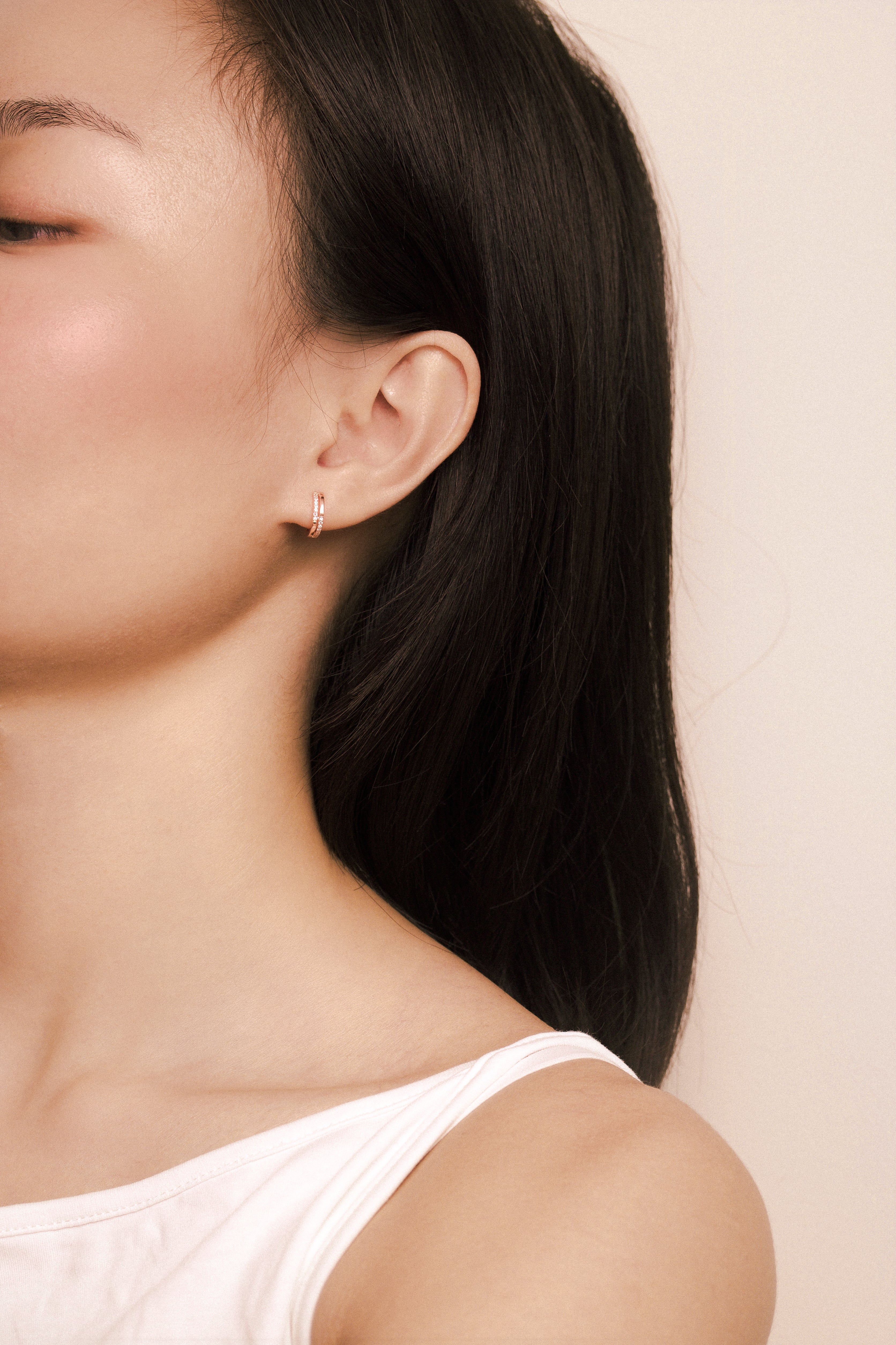 Fine jewellery, silver jewellery plated with rose gold, hypoallergenic, tarnish-free, close-up front view of a Rose gold hoop earrings with embedded crystals worn on a person's ear