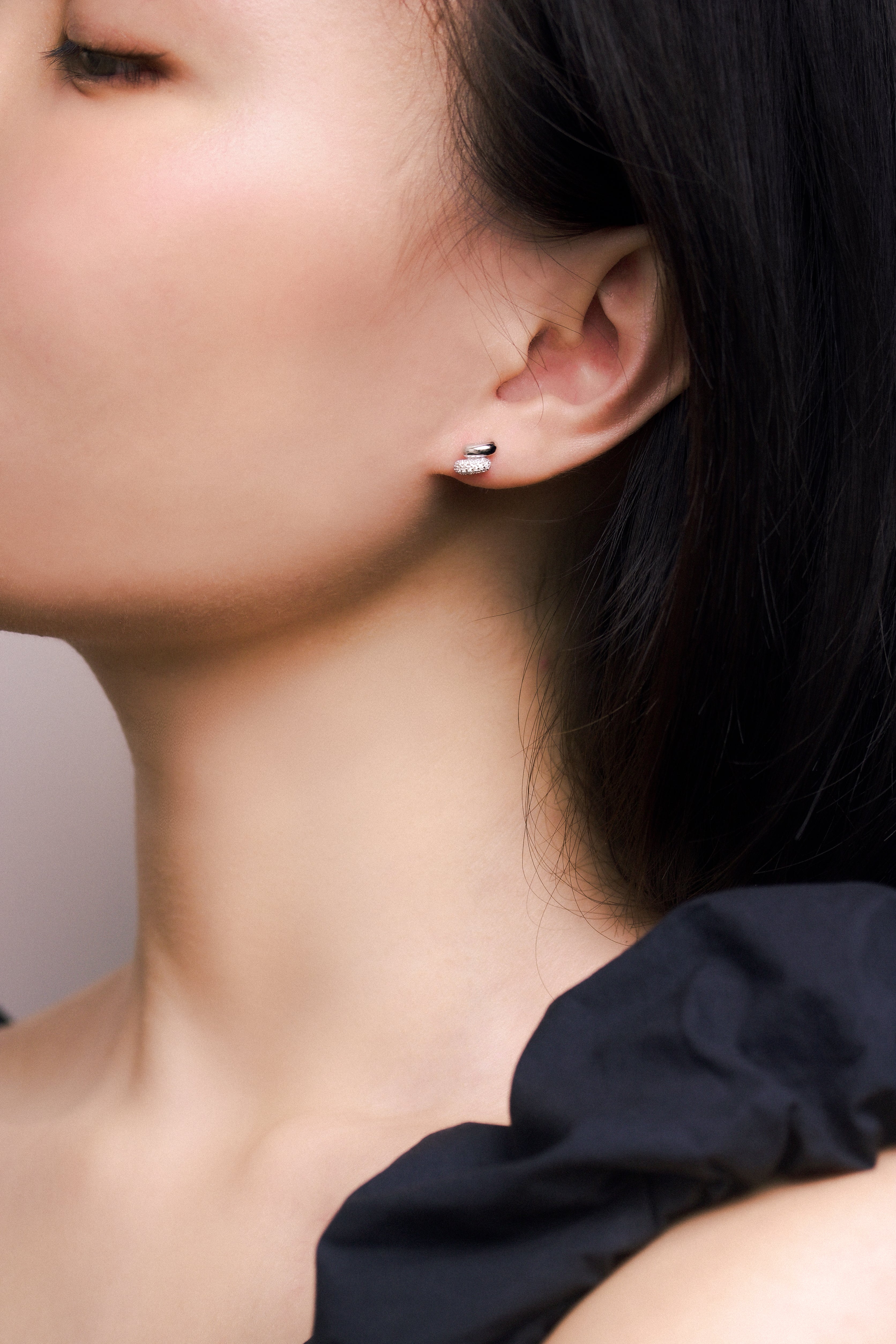 Fine jewellery, silver jewellery, hypoallergenic, tarnish-free, zoomed out front view of a Pair of silver ear studs embedded with crystals worn on a person's ear