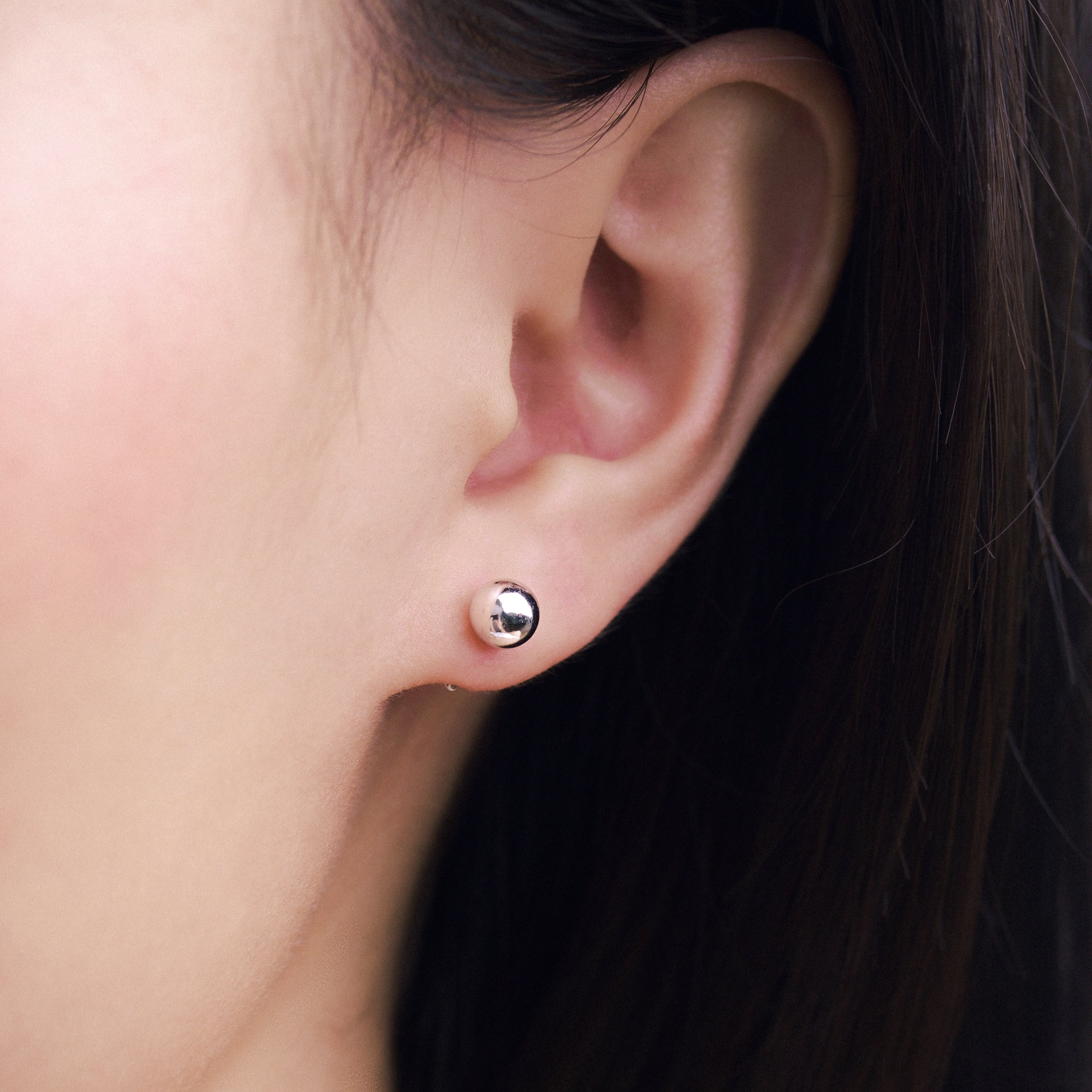 Fine jewellery, silver jewellery, hypoallergenic, tarnish-free, Close-up front view of an ear wearing a silver stud earring with a blurred background
