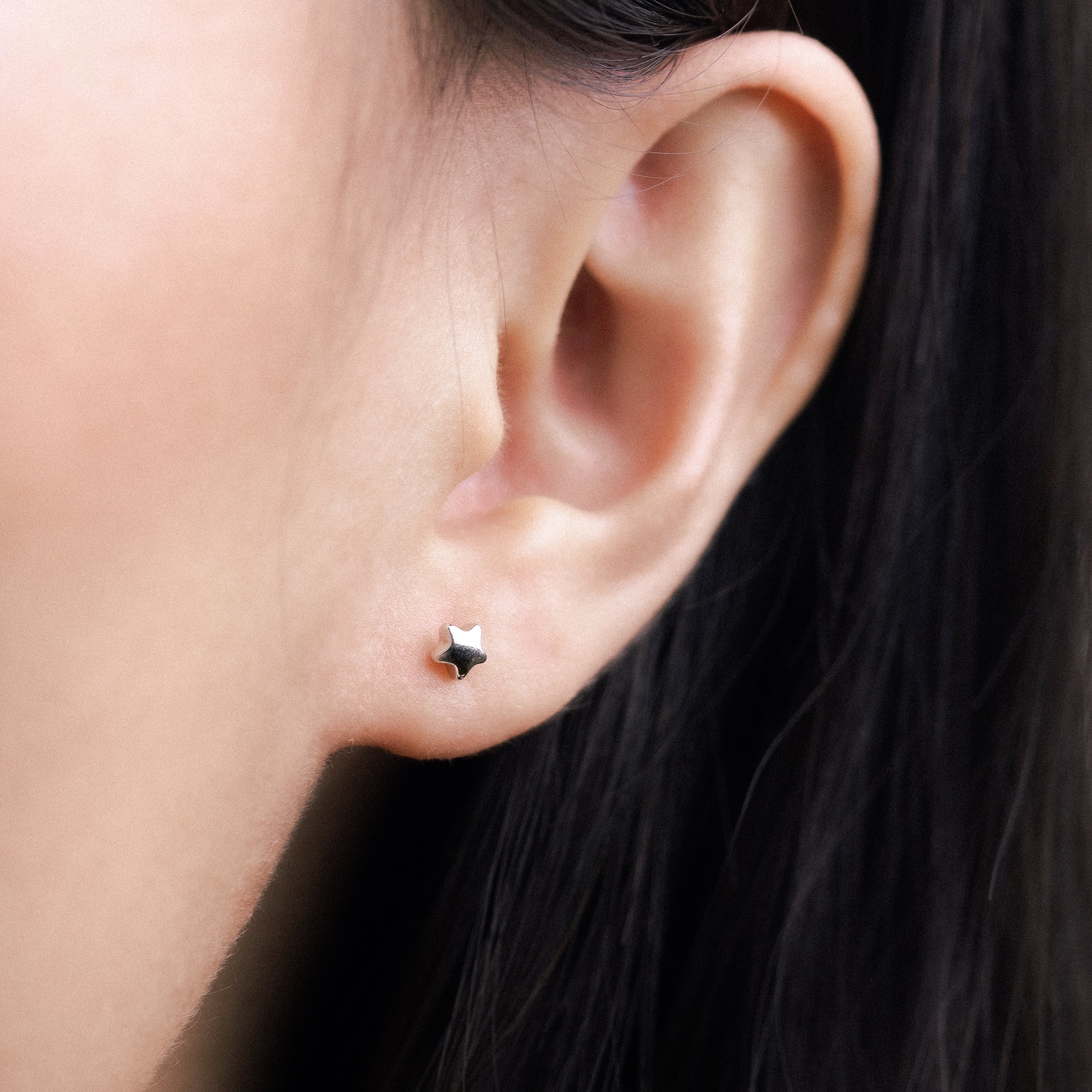Fine jewellery, silver jewellery, hypoallergenic, tarnish-free,
Close-up front view of a Star-shaped earrings worn on a person's ear