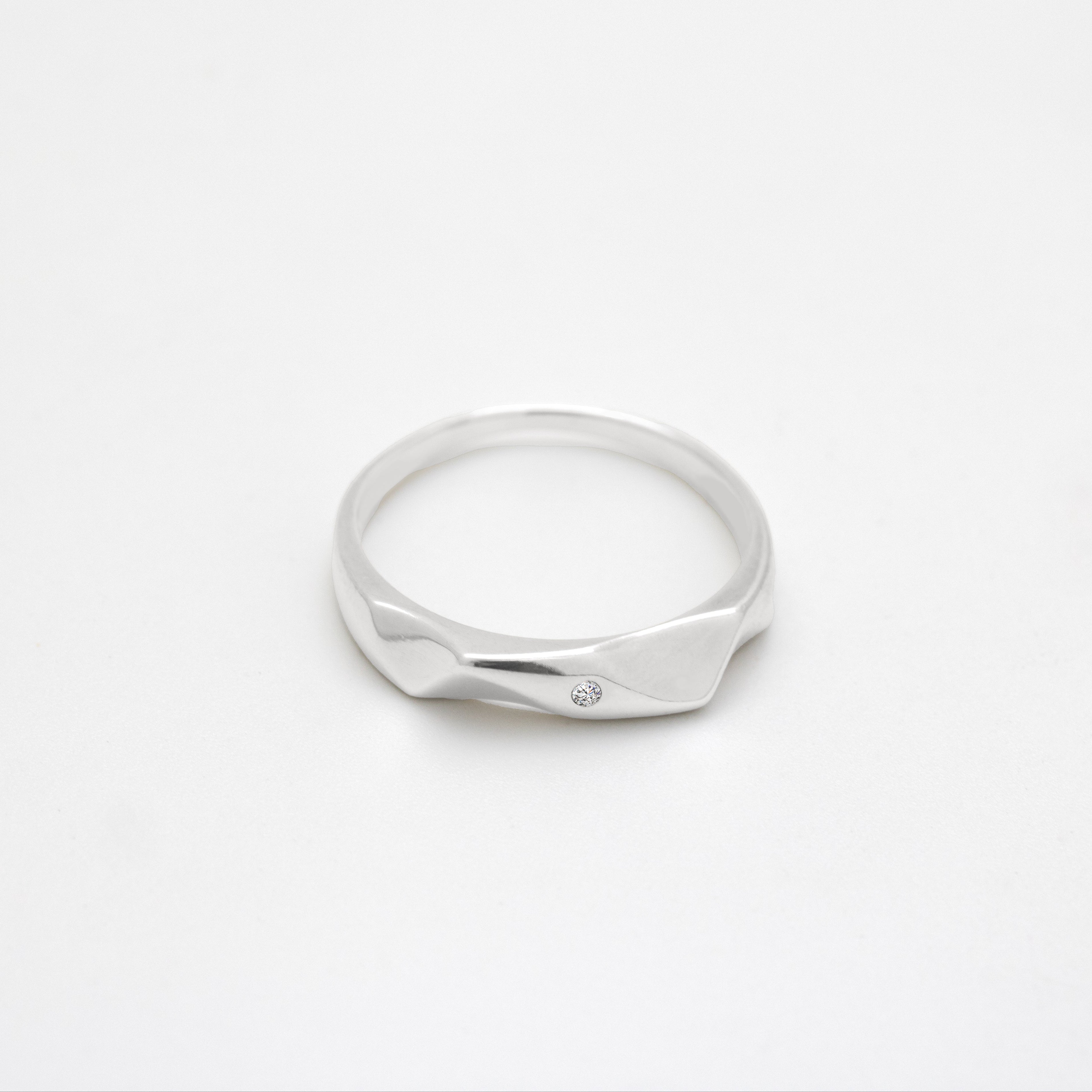 Silver ring with a diamond on a white background, close up top down view